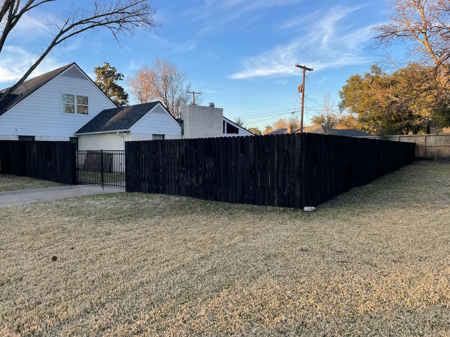 Black-stained wood privacy fence with a matching metal walkway gate