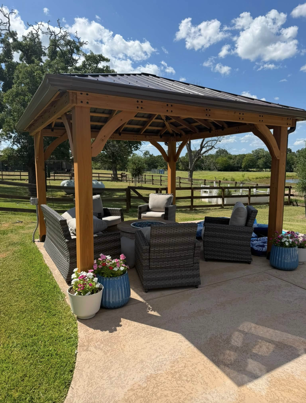 Cedar pavilion with metal roof over a fire pit seating area on a ranch