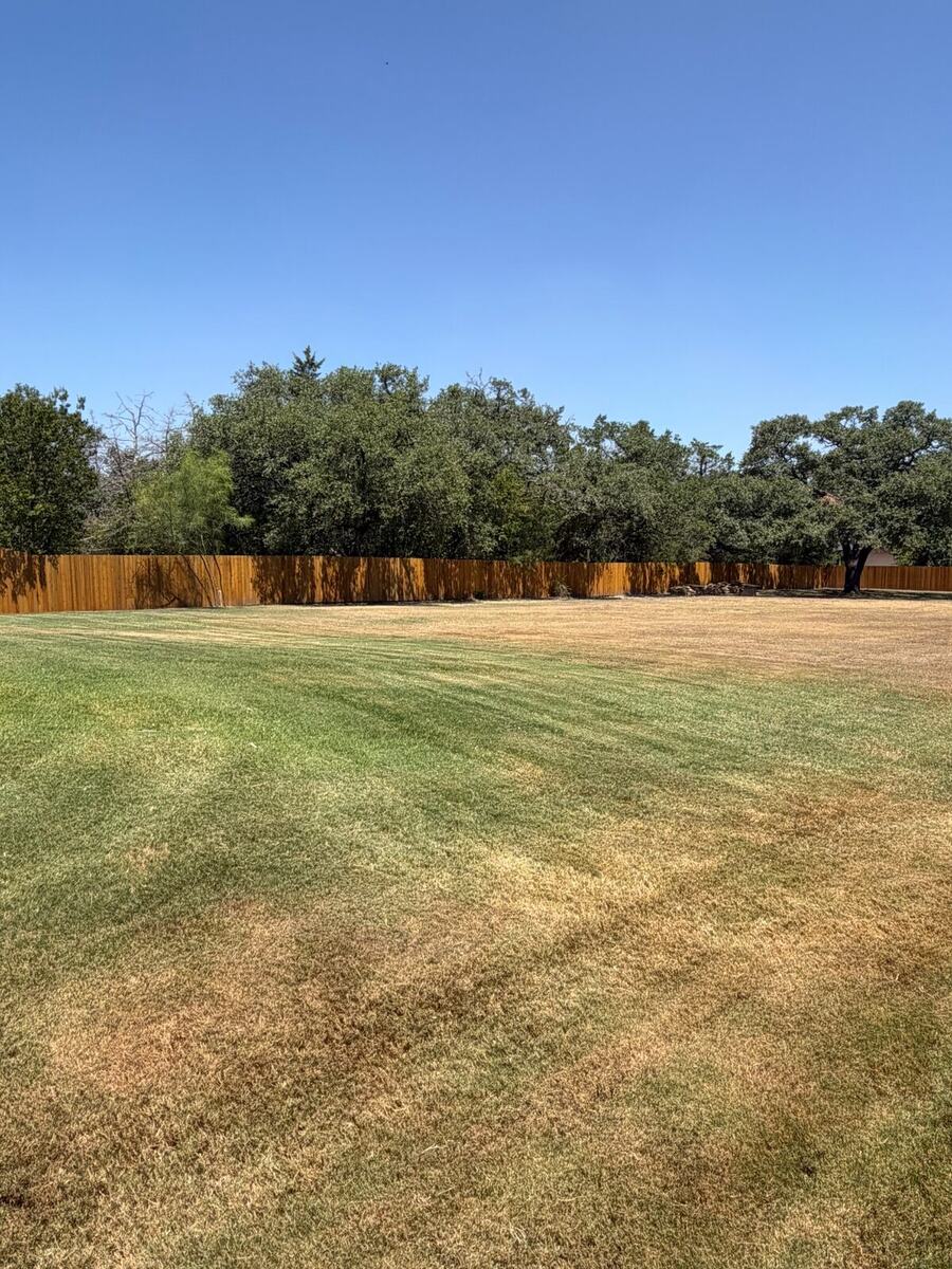 Freshly stained cedar perimeter fence enclosing a large Brazos Valley property