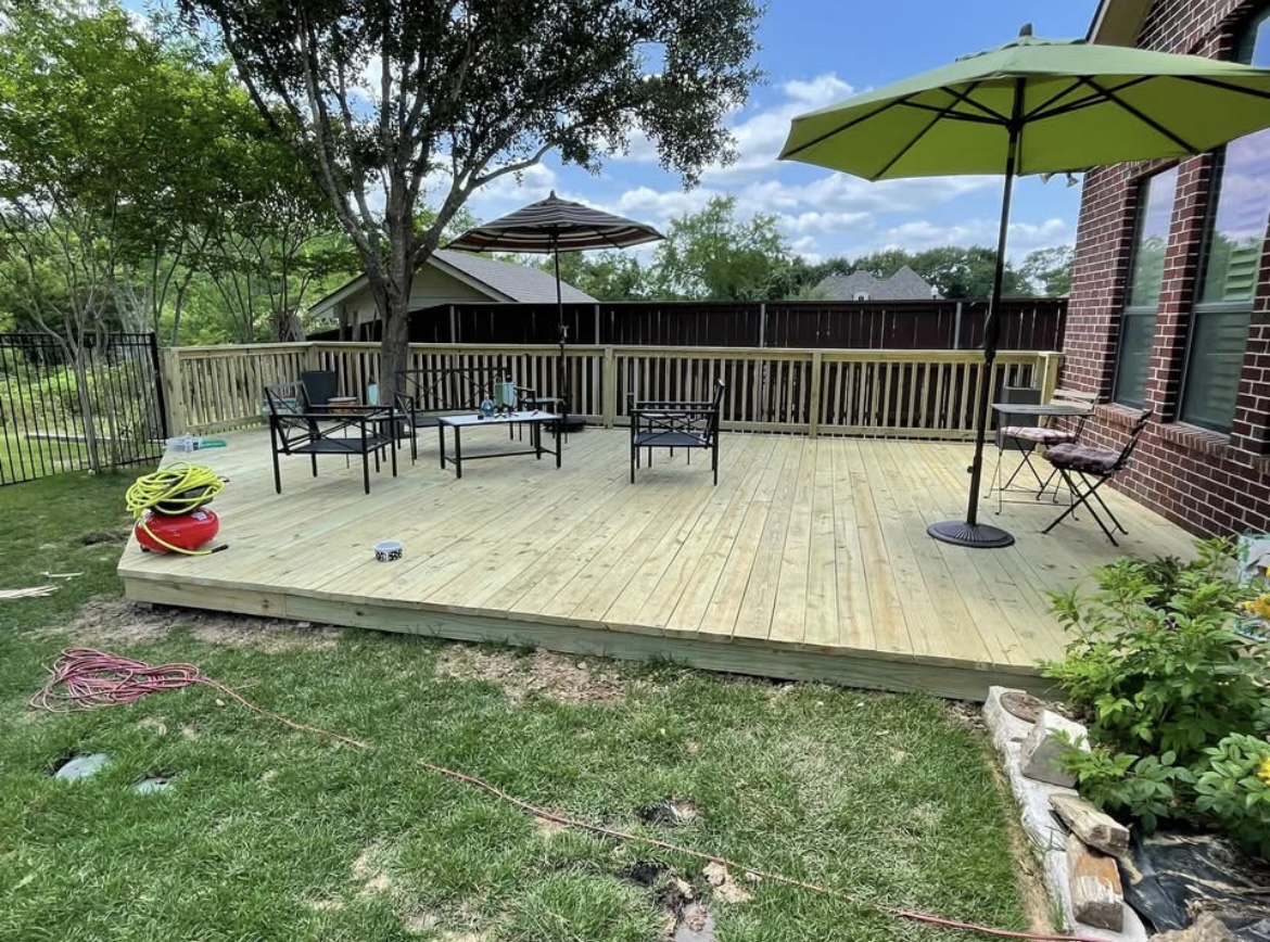 Spacious backyard wood deck with patio furniture and umbrellas