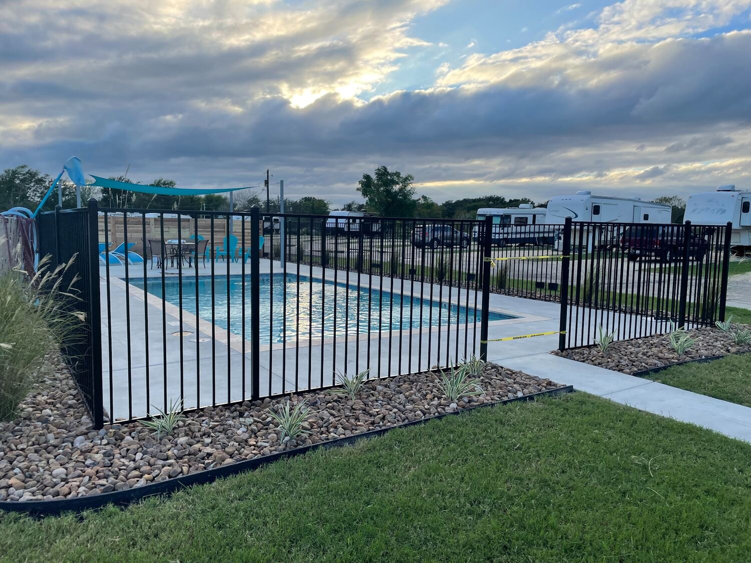 Black metal safety fence surrounding a swimming pool at sunset