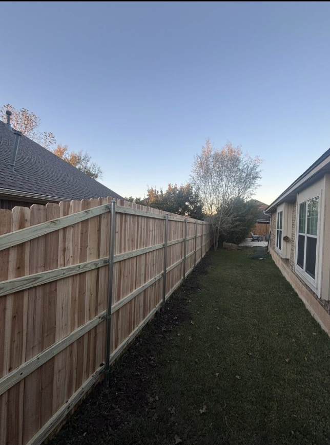 New wood privacy fence running along a side yard at dusk