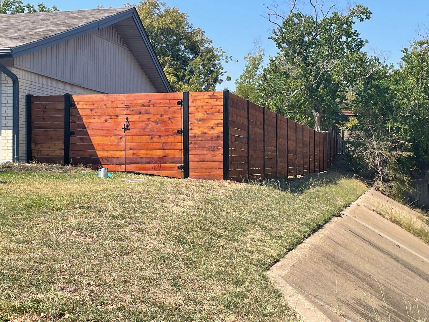Stained horizontal wood privacy fence with a custom double gate