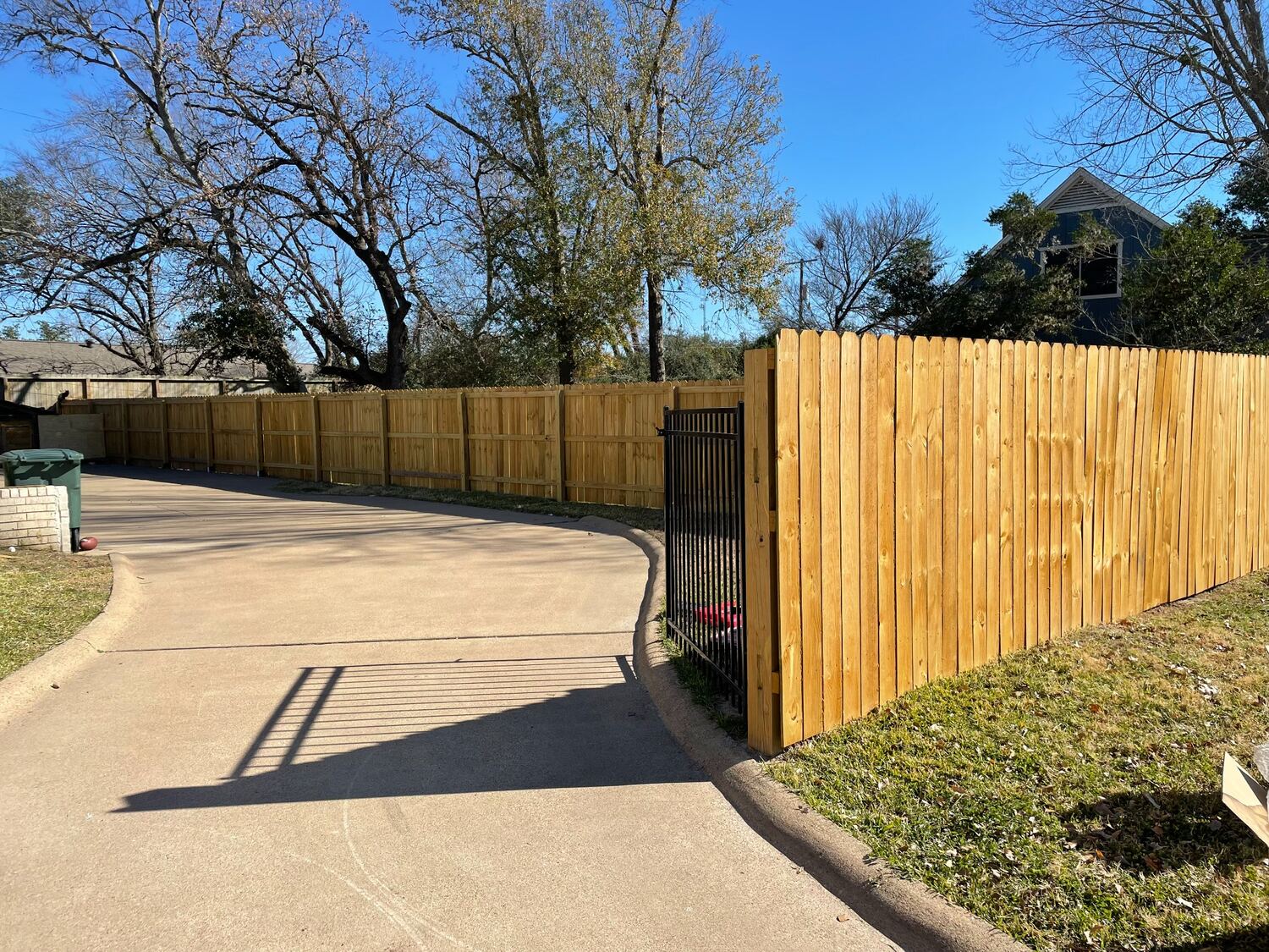 Wood privacy fence paired with a black metal driveway gate
